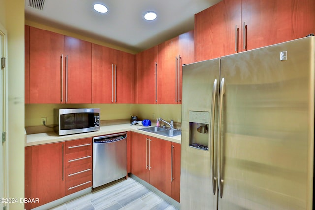 kitchen featuring appliances with stainless steel finishes, sink, and light hardwood / wood-style flooring