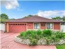 single story home featuring a garage, driveway, and a vegetable garden