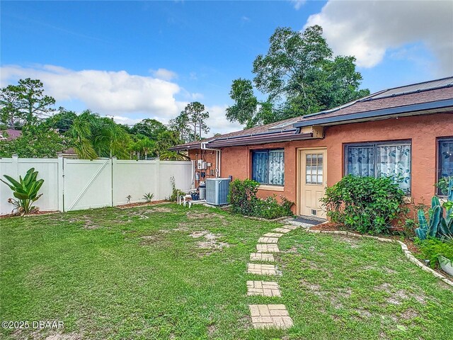 view of yard featuring a gate, fence, and central AC