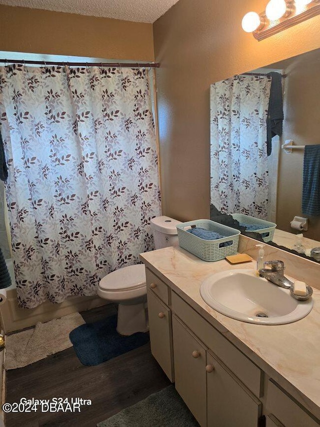 full bathroom featuring hardwood / wood-style flooring, shower / tub combo, a textured ceiling, vanity, and toilet