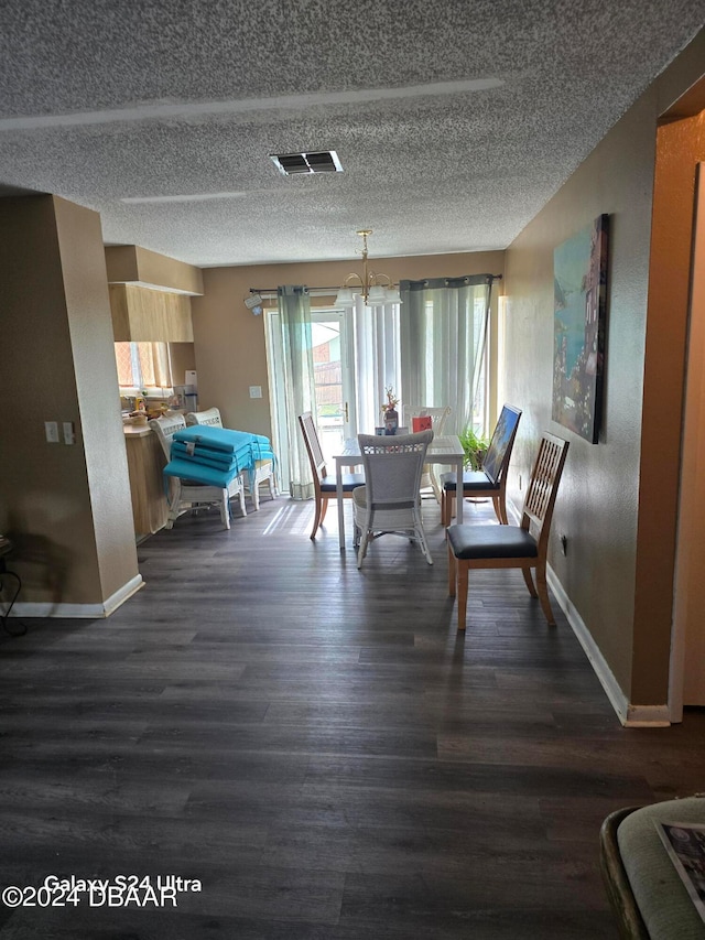 dining area featuring dark wood-type flooring, an inviting chandelier, and a textured ceiling