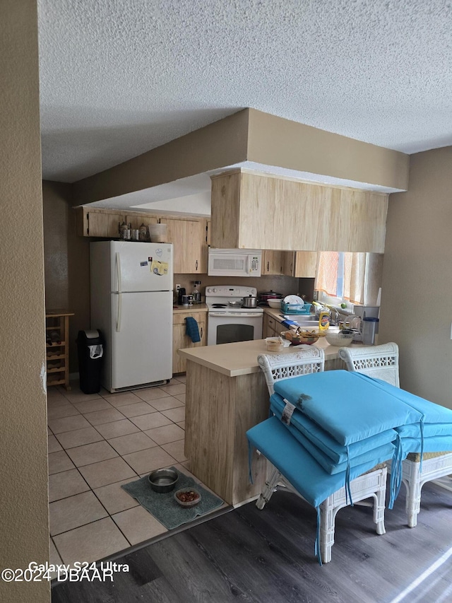 1461 Felton St, Deltona, FL 32725 - kitchen with white appliances, a textured ceiling, a peninsula, light brown cabinets, and light wood finished floors