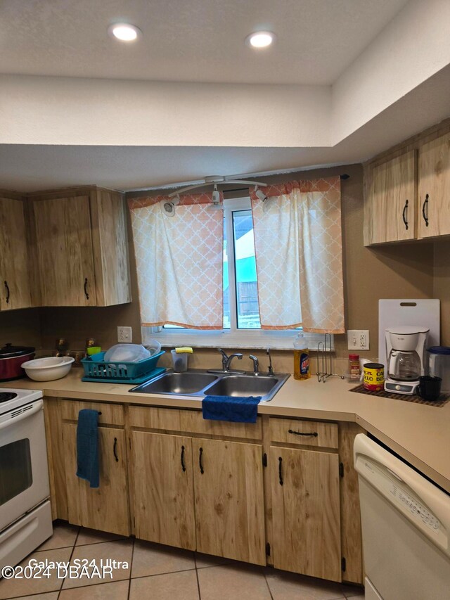 kitchen featuring white appliances, sink, and light tile patterned flooring