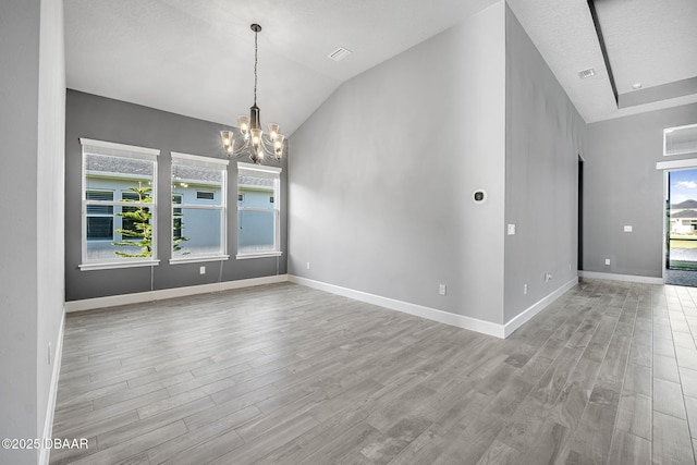 spare room featuring lofted ceiling, wood finished floors, baseboards, and a chandelier