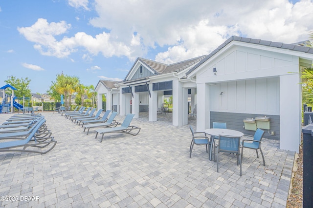 view of patio with outdoor dining space and playground community