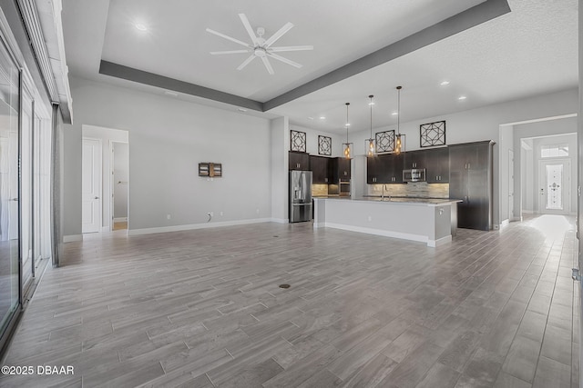 unfurnished living room featuring a ceiling fan, a sink, recessed lighting, light wood-style floors, and baseboards