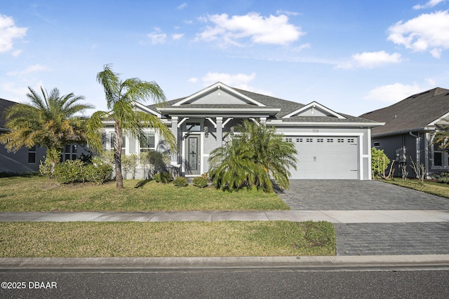 view of front of home featuring decorative driveway, a front yard, an attached garage, and stucco siding