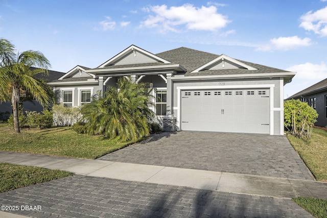 view of front of property featuring stucco siding, a front yard, decorative driveway, and a garage