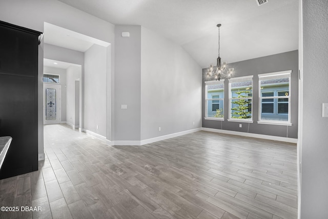 interior space with wood finished floors, visible vents, baseboards, lofted ceiling, and a chandelier