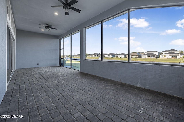 unfurnished sunroom featuring a residential view and a ceiling fan