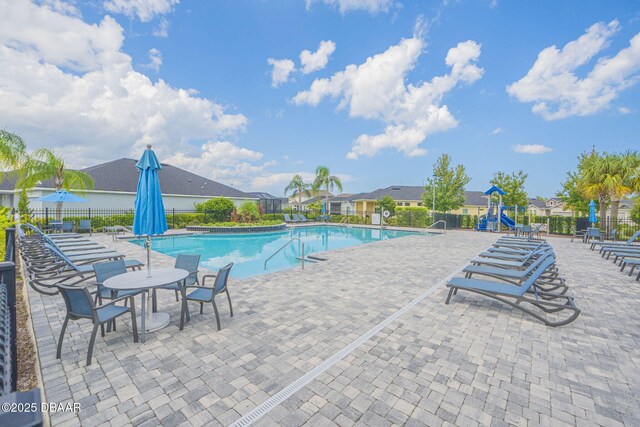 pool featuring a patio, fence, playground community, and a residential view