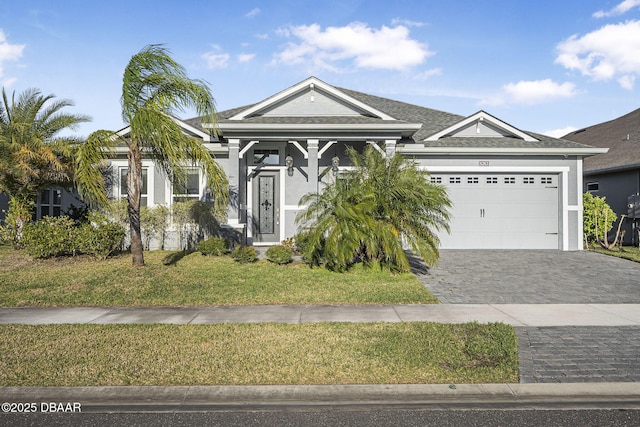 view of front of home featuring stucco siding, a front yard, decorative driveway, and a garage