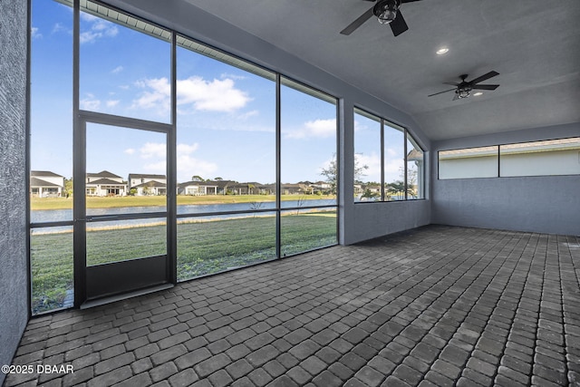 unfurnished sunroom with a residential view, a water view, and ceiling fan