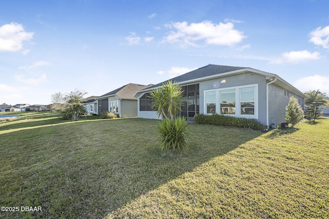 ranch-style home featuring a front yard, a sunroom, and stucco siding