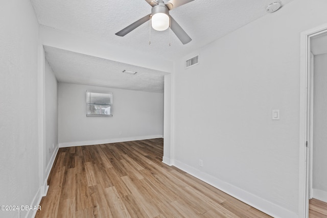 spare room featuring light wood-type flooring, a textured ceiling, and ceiling fan