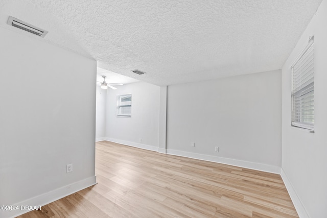 empty room with ceiling fan, a textured ceiling, and light wood-type flooring