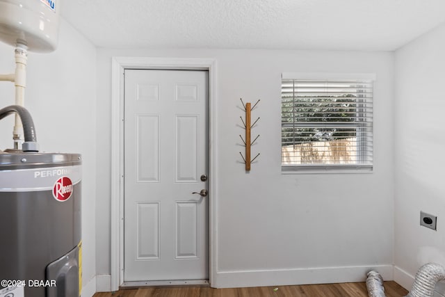 laundry room with hookup for an electric dryer, water heater, a textured ceiling, and hardwood / wood-style flooring