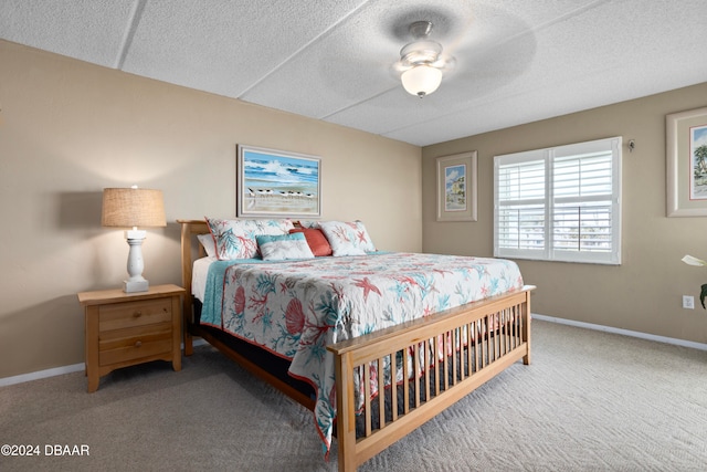 carpeted bedroom featuring ceiling fan and a textured ceiling