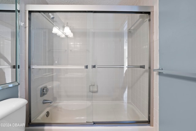 bathroom with toilet and bath / shower combo with glass door