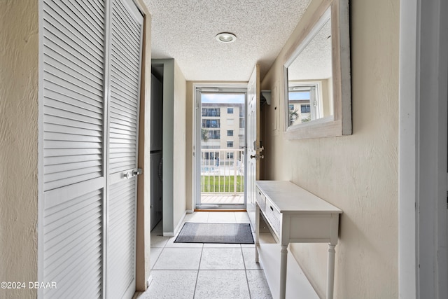 doorway with light tile patterned floors and a textured ceiling