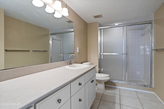 bathroom with tile patterned floors, a textured ceiling, toilet, vanity, and a shower with shower door