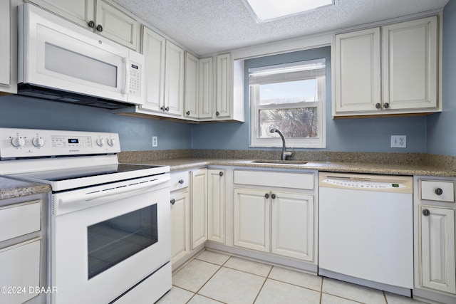 kitchen with a textured ceiling, white appliances, sink, and light tile patterned floors