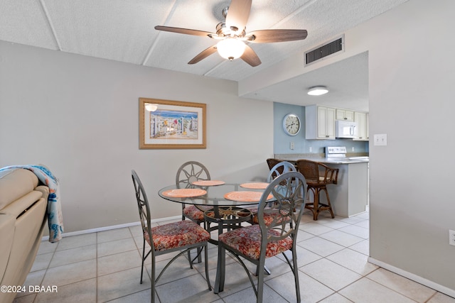 tiled dining room featuring ceiling fan and a textured ceiling