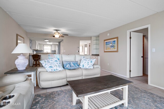 tiled living room with ceiling fan and sink