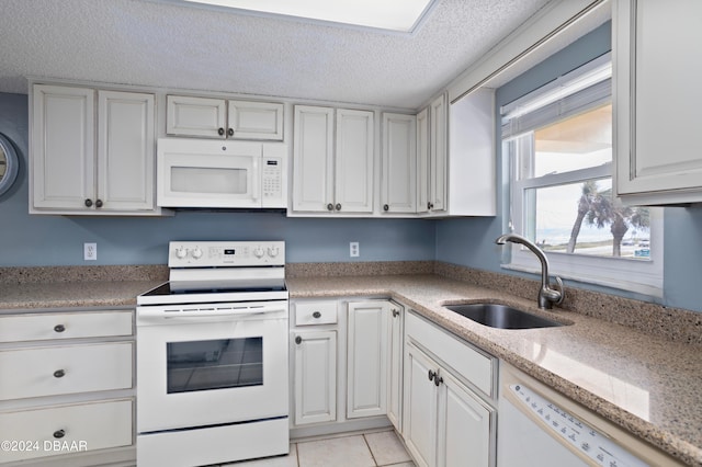 kitchen featuring white cabinets, light tile patterned flooring, white appliances, and sink