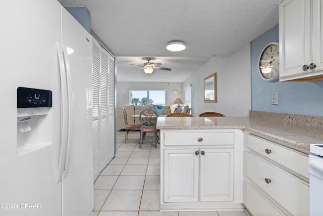 kitchen with ceiling fan, white cabinetry, white refrigerator with ice dispenser, and kitchen peninsula