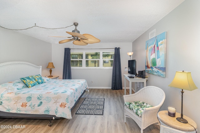 bedroom featuring ceiling fan, a textured ceiling, and light wood-type flooring