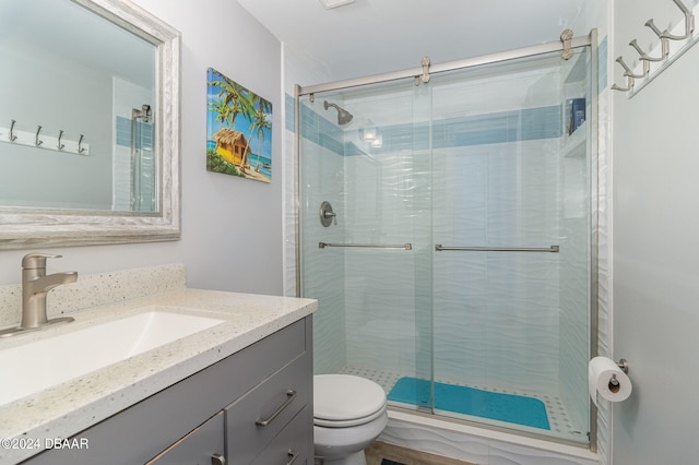 bathroom with a shower with shower door, vanity, and toilet