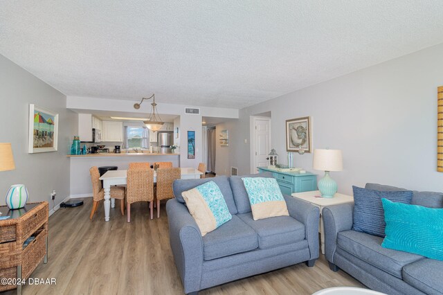 living room with light hardwood / wood-style flooring and a textured ceiling