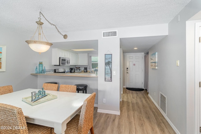 dining space featuring a textured ceiling and light hardwood / wood-style floors