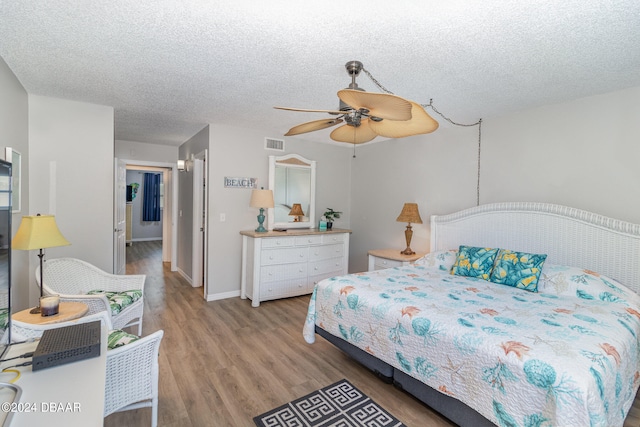 bedroom featuring light hardwood / wood-style floors, a textured ceiling, and ceiling fan