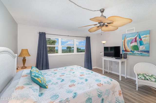 bedroom with hardwood / wood-style flooring, ceiling fan, and a textured ceiling