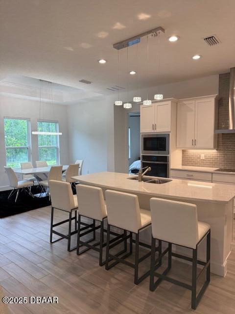437 Aquamarine Way, Daytona Beach, FL 32124 - kitchen with stainless steel microwave, light wood finished floors, wall chimney range hood, white cabinetry, and recessed lighting