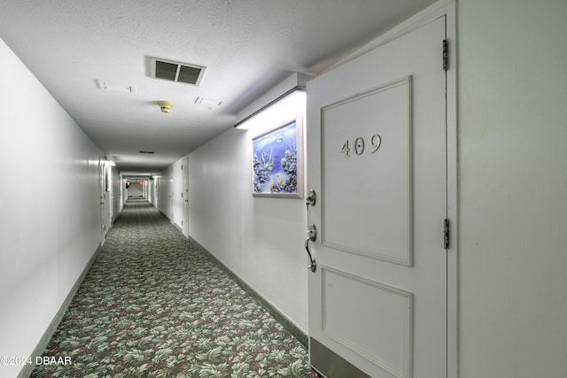 hall featuring carpet and a textured ceiling