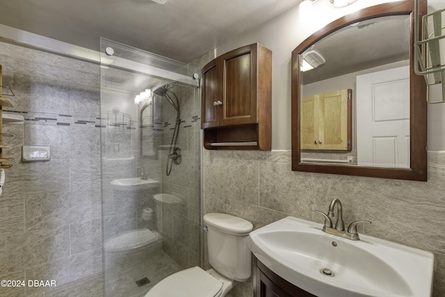 bathroom with vanity, a shower with shower door, tile walls, and toilet