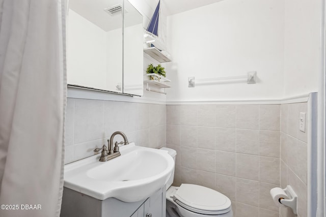 bathroom featuring vanity, tile walls, and toilet