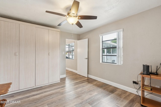 bedroom with ceiling fan, light hardwood / wood-style floors, and multiple windows