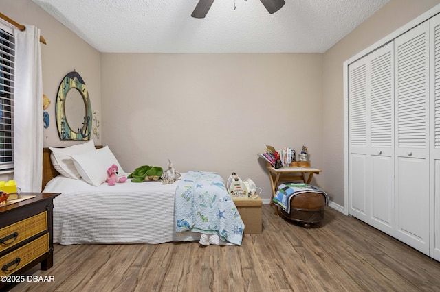 bedroom featuring ceiling fan, a closet, wood-type flooring, and a textured ceiling