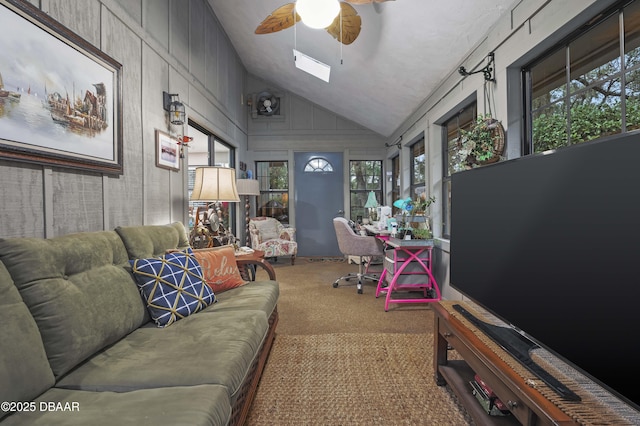 carpeted living room with wooden walls, ceiling fan, and vaulted ceiling