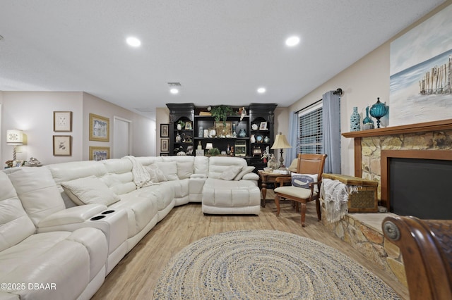 living room with a textured ceiling, light hardwood / wood-style floors, and a fireplace