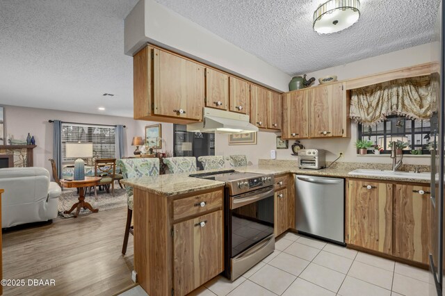 kitchen featuring kitchen peninsula, stainless steel dishwasher, a textured ceiling, sink, and electric range