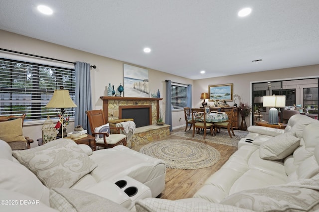 living room with a fireplace, wood-type flooring, and a textured ceiling