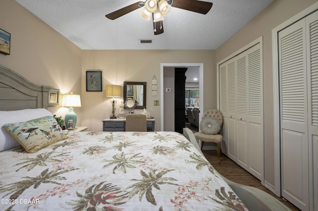 bedroom featuring a textured ceiling, two closets, ceiling fan, and hardwood / wood-style flooring