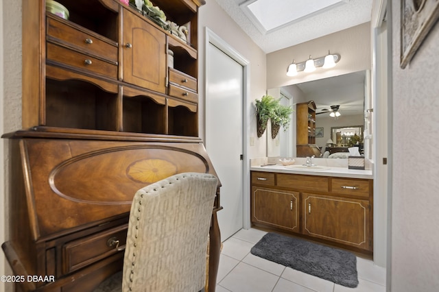 bathroom with a skylight, a textured ceiling, vanity, ceiling fan, and tile patterned flooring