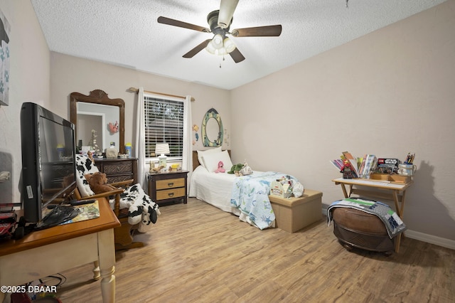 bedroom with ceiling fan, light hardwood / wood-style flooring, and a textured ceiling