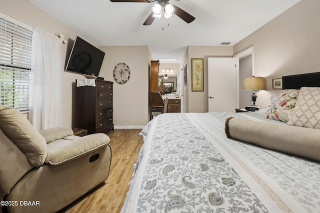 bedroom with a textured ceiling, light wood-type flooring, and ceiling fan